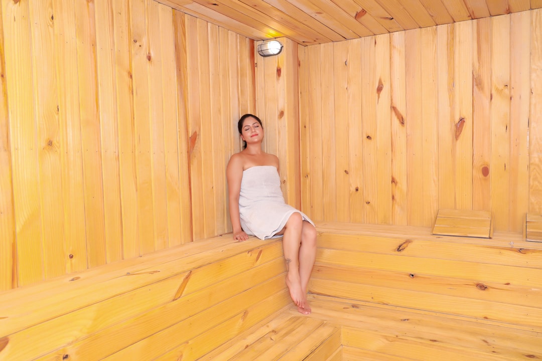 A woman sitting in a sauna with a towel on